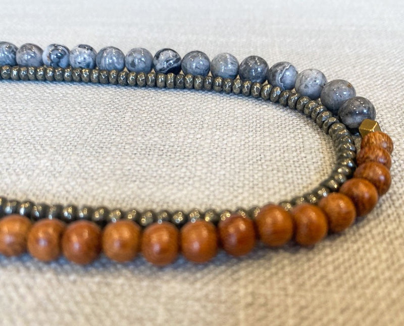 side view of gemstone bead necklace comprising grey landscape jasper, exotic wood and metallics