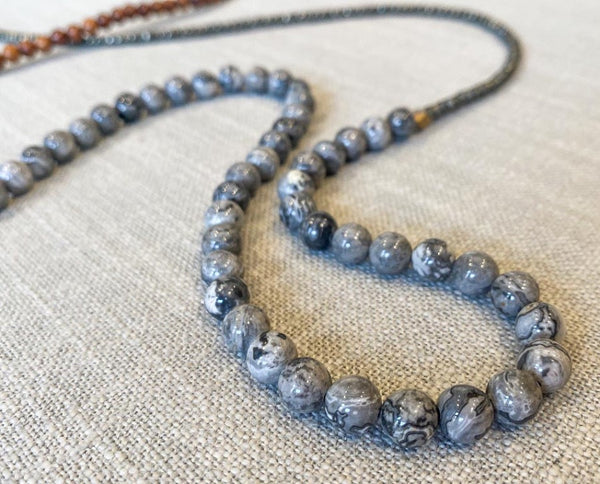 closeup of gemstone bead necklace comprising grey landscape jasper, exotic wood and dark grey pyrite