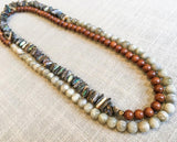 top view of gemstone bead necklace comprising off-white siberian moonstone, exotic wood and black tahitian shell nuggets