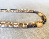 side view of gemstone bead necklace comprising beige shell, black ethiopian opal and dark bronze