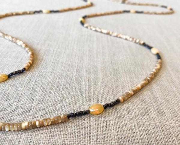 closeup of gemstone bead necklace comprising beige shell, ethiopian opal and dark bronze 