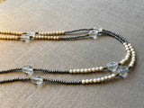 side view of gemstone bead necklace comprising clear rock quartz, beige fossil jasper and metallics