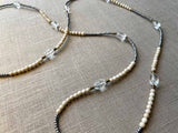 closeup of gemstone bead necklace comprising clear rock quartz, beige fossil jasper and metallics