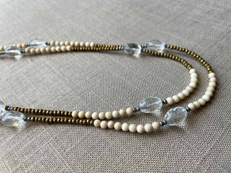 side view of gemstone bead necklace comprising clear rock quartz, beige fossil jasper and metallics