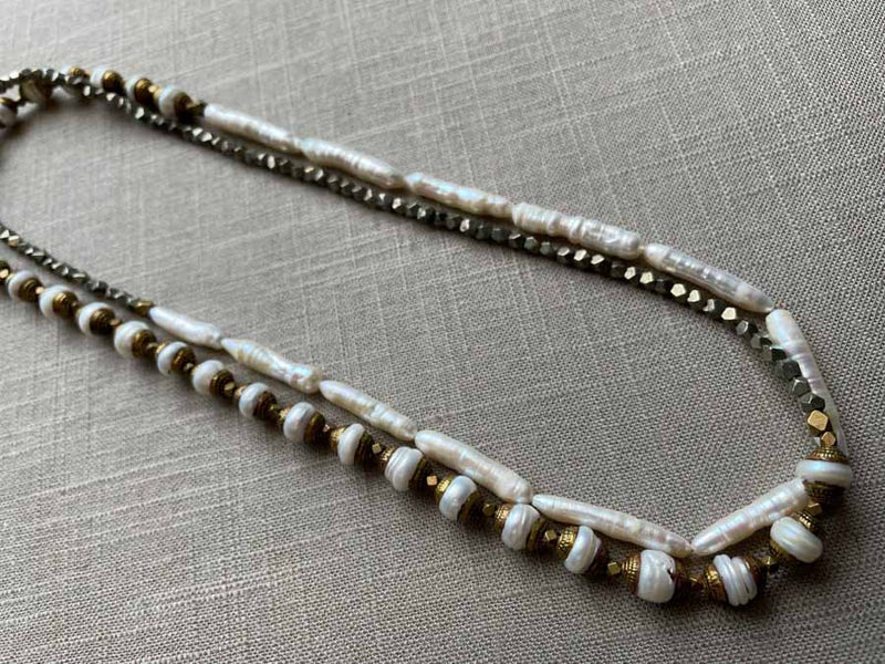 top view of gemstone bead necklace comprising white antique capped pearl, white stick pearl, dark grey pyrite