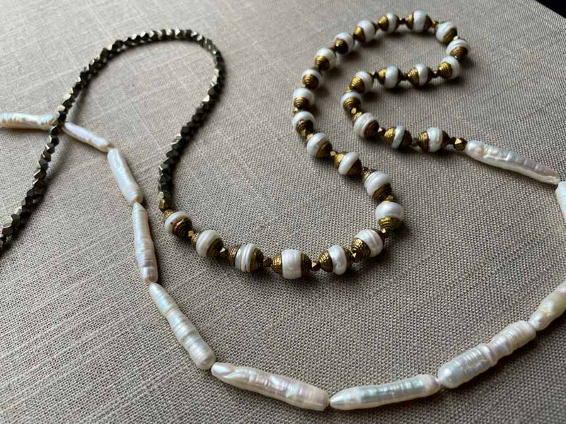 closeup of gemstone bead necklace comprising white antique capped pearl, white stick pearl, dark grey pyrite