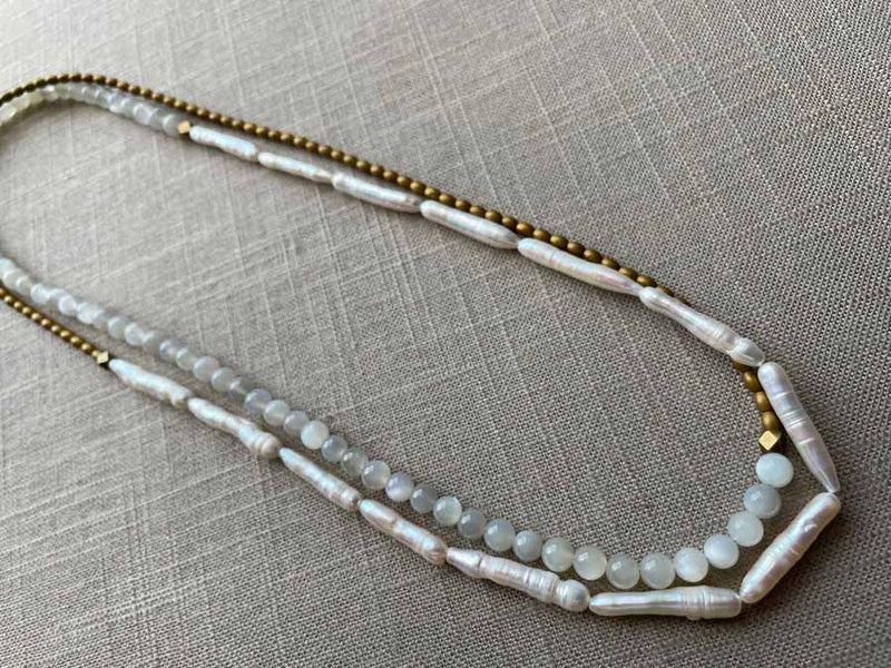 top view of gemstone bead necklace comprising white moonstone, white stick pearl, gold hematite