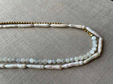 side view of gemstone bead necklace comprising white moonstone, white stick pearl, gold hematite