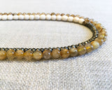 side view of gemstone bead necklace comprising white conch shell, metallics and neutral rutilated quartz