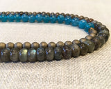 side view of gemstone bead necklace comprising iolite, matte bronze hematite and green labradorite