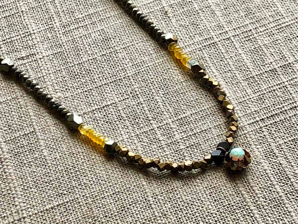 closeup of antique opal pendant hung on metallic bead choker