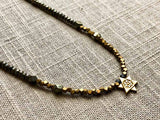 closeup of antique Star of David pendant hung on metallic bead choker