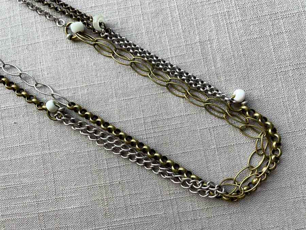 closeup of 64"L mixed metal chain necklace with white padre beads