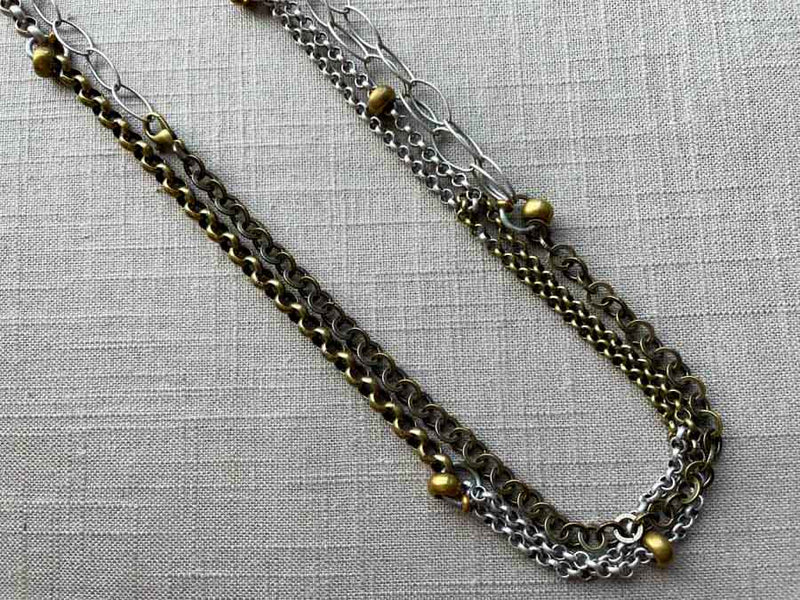 closeup of 64"L mixed metal chain necklace with bronze beads