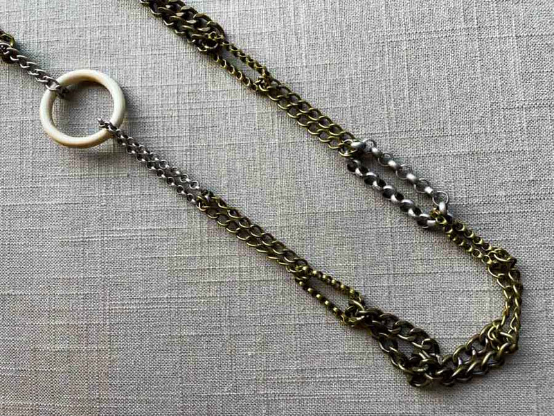 closeup of fossil ivory ring necklace with mixed metal chain mix