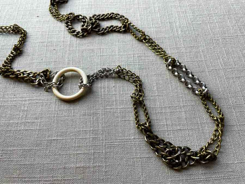 closeup of fossil ivory ring necklace with mixed metal chain mix