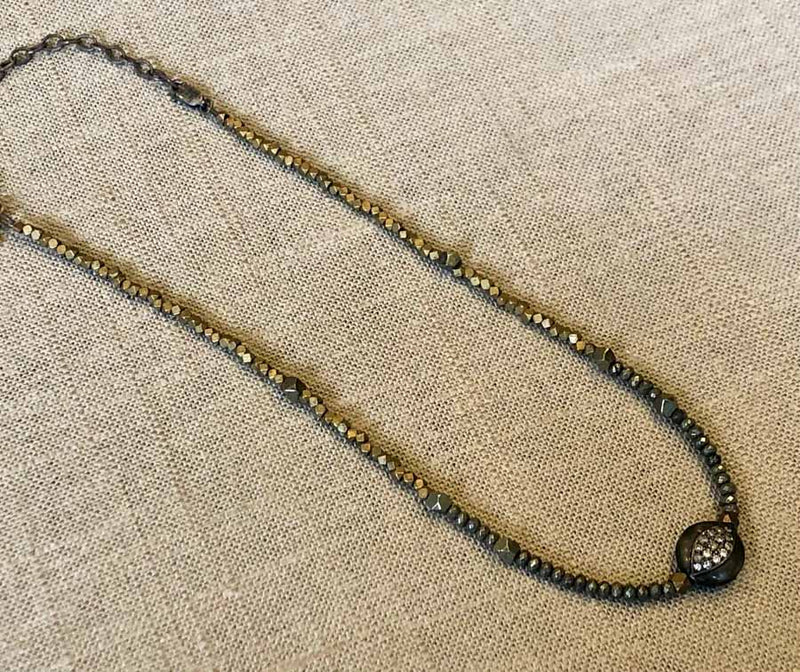 top view  of pave evil eye pendant hung on metallic bead choker 