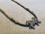 closeup of pave horse pendant hung on metallic bead choker