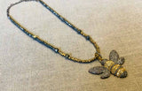 top view of pave bee pendant hung on metallic bead choker