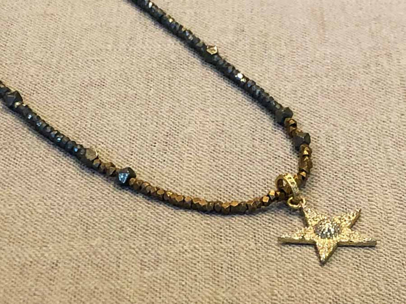 closeup of pave star pendant hung on metallic bead choker