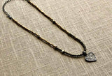 top view of pave heart pendant hung on metallic bead choker