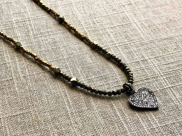 closeup of pave heart pendant hung on metallic bead choker