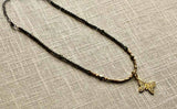 top view of pave butterfly pendant hung on metallic bead choker