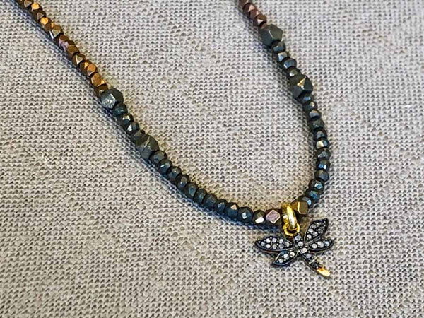 closeup of pave dragonfly pendant hung on metallic bead choker