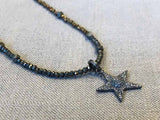 closeup of pave star pendant hung on metallic bead choker