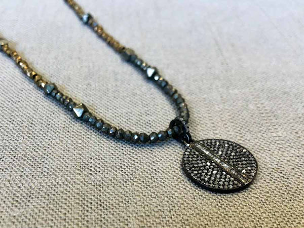 closeup of pave disc pendant hung on metallic bead choker