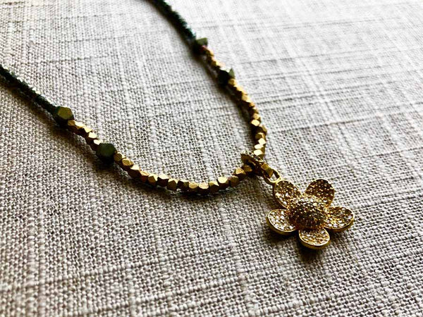 closeup of pave flower pendant hung on metallic bead choker