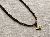 closeup of pave evil eye pendant hung on metallic bead choker