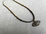 top view of silver pave evil eye pendant hung on metallic bead choker