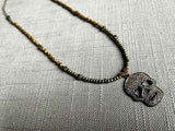 top view of pave skull pendant hung on metallic bead choker