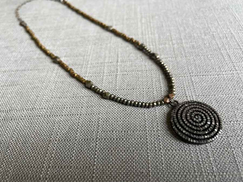 top view of pave spiral pendant hung on metallic bead choker