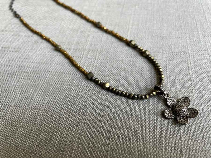 top view of pave flower pendant hung on a metallic bead choker