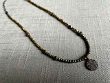 top view of pave disc pendant hung on a metallic bead choker