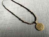 top view of pave disc pendant hung on a metallic bead choker