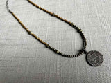 top view of pave disc pendant hung on a metallic bead choker