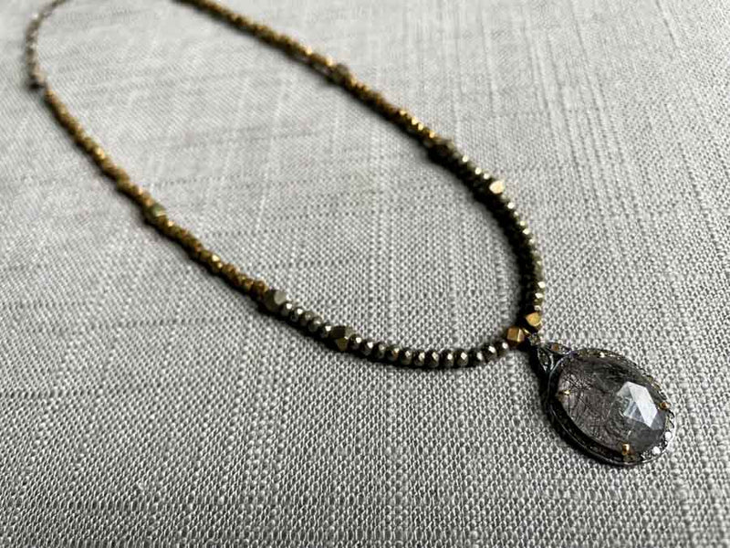 top view of pave tourmalated quartz pendant hung on a metallic bead choker