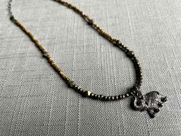 top view of pave elephant pendant with ruby eye hung on a metallic bead choker