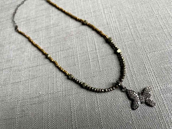 top view of pave butterfly pendant hung on a metallic bead choker