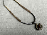 top view of diamond slice flower pendant hung on a metallic bead choker