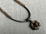 closeup of diamond slice flower pendant hung on a metallic bead choker