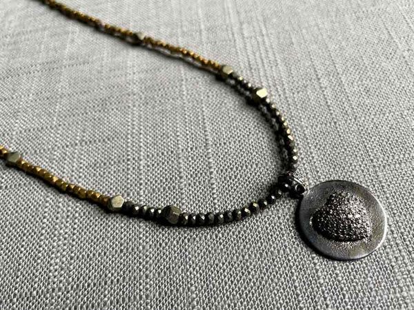 closeup of pave puff heart pendant hung on a metallic bead choker