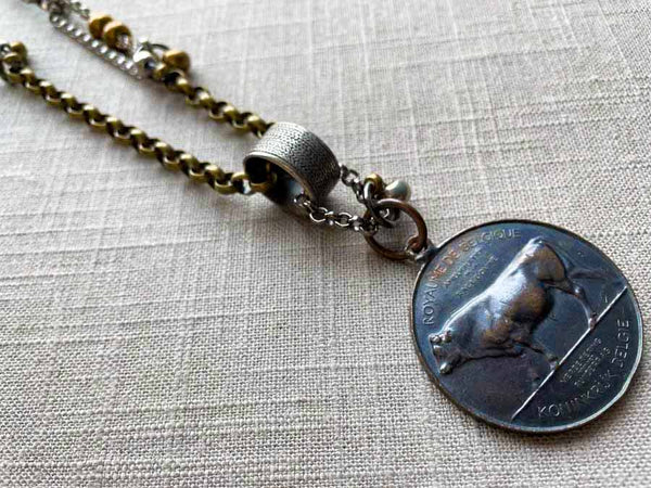 closeup of antique bronze bull medallion pendant on chain mix