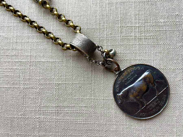 closeup of antique bronze bull medallion pendant on chain mix