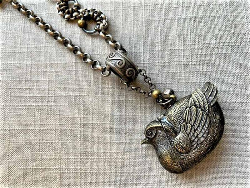 closeup of bird match safe pendant on chain mix