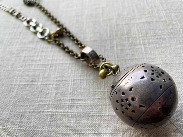 closeup of antique sterling silver globe tea caddy on chain mix