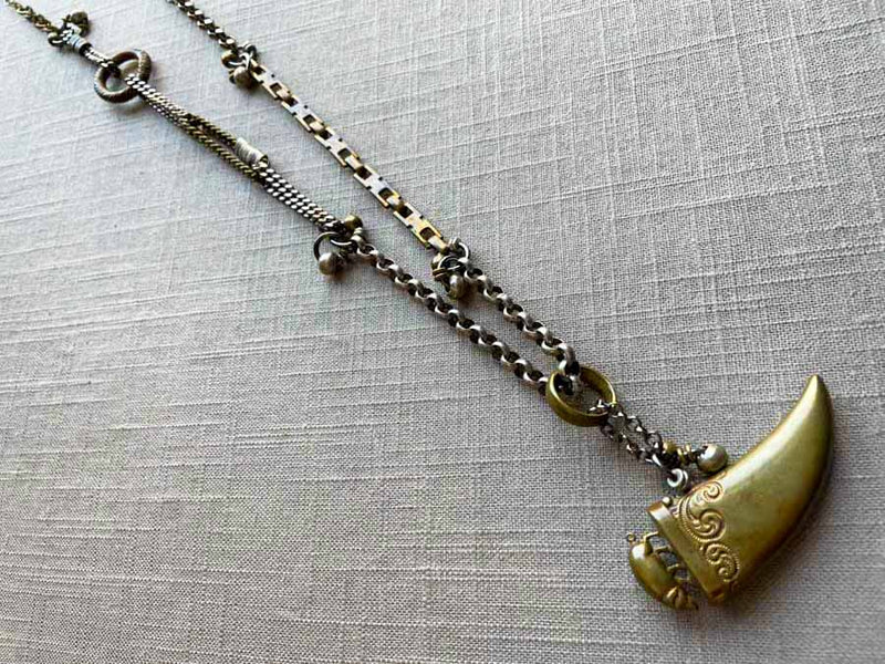 top view closeup of antique bronze tooth match safe with pig pendant on chain mix